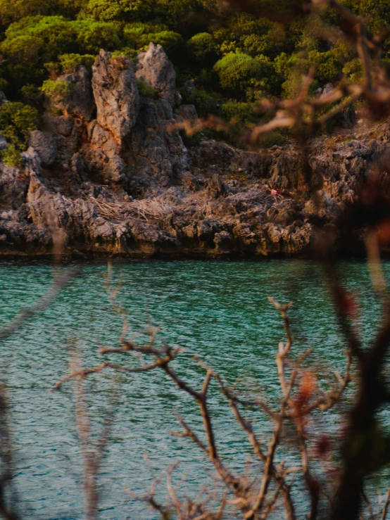 an airplane flying over a lake surrounded by rocks and grass