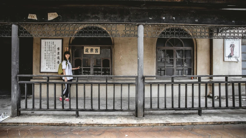 the girl walking down the street is past a building with two windows