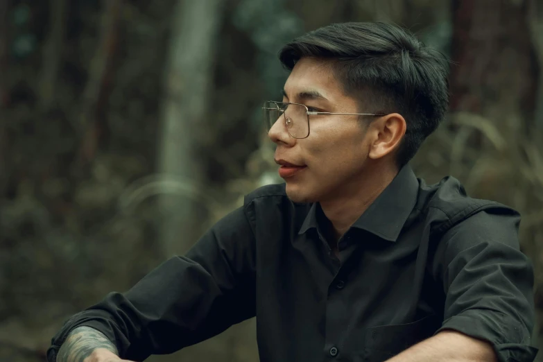 a man sitting in the woods holding his cell phone