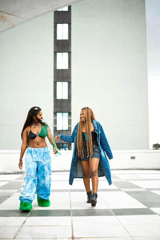 two women are walking towards a white building