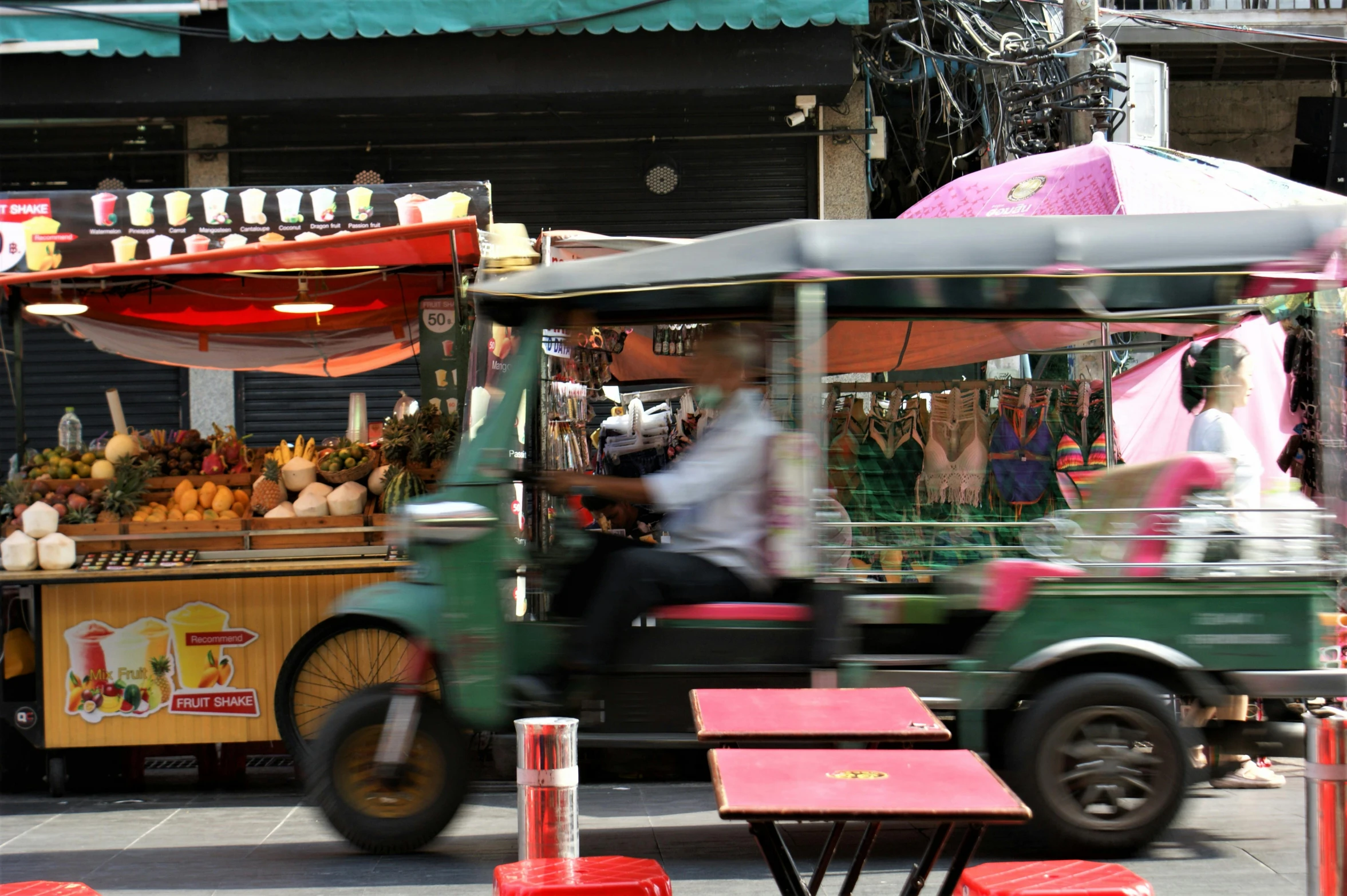 people ride in an ice cream cart on a busy street