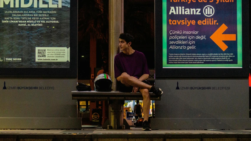 a man sitting on top of a bench under posters