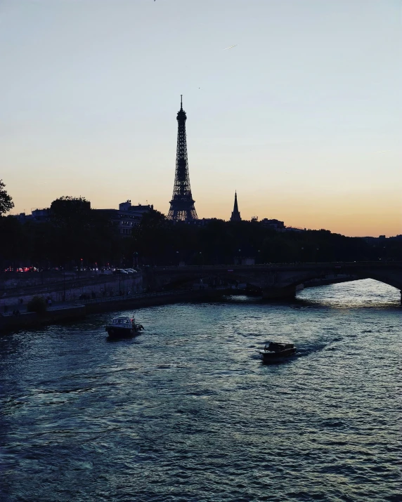 the eiffel tower is in the distance, overlooking the water and boats