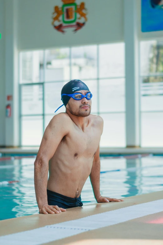 a man in swimming gear and a hat sitting on top of a board