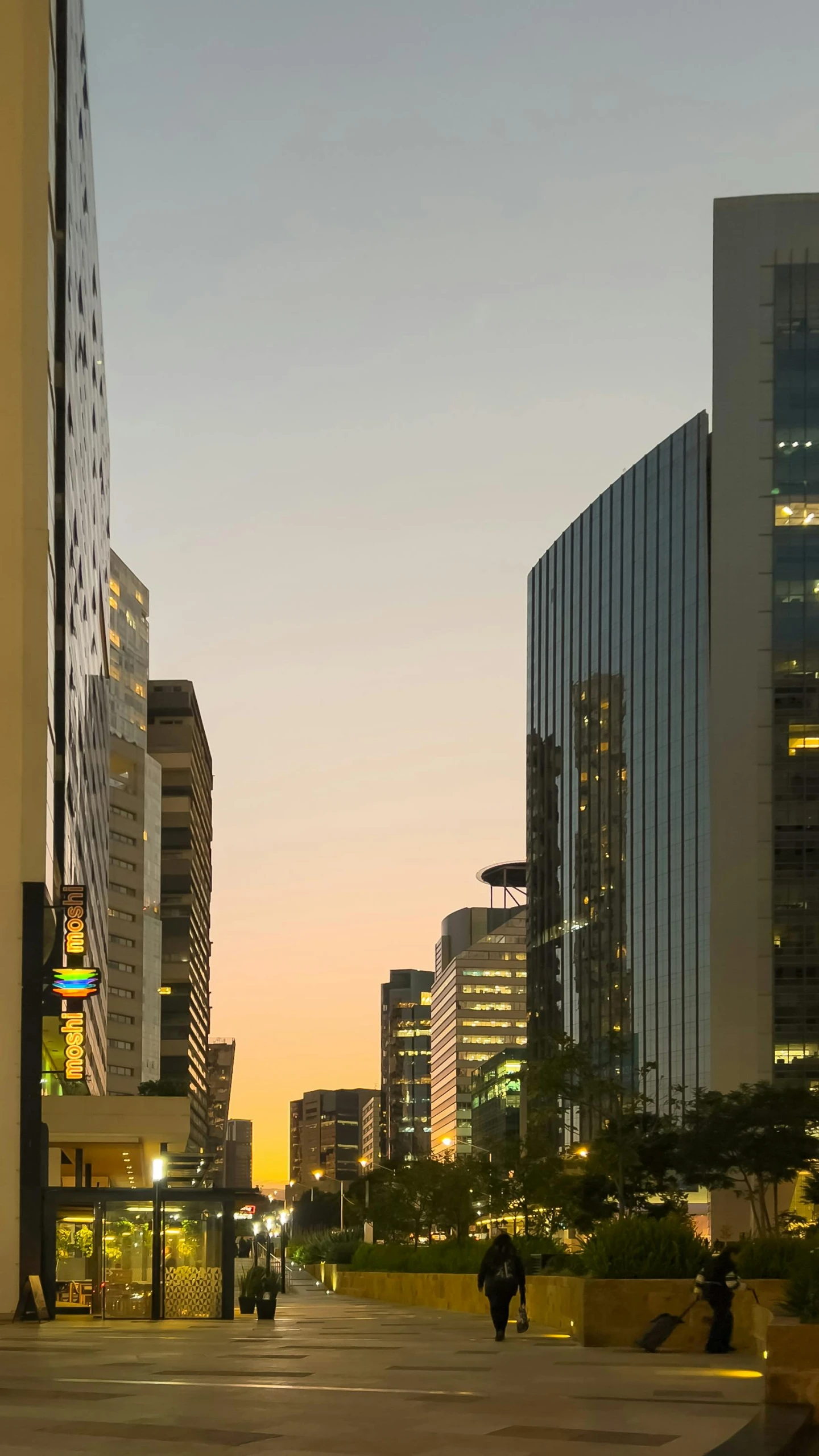 city skyline with skyscrs and people walking at dusk