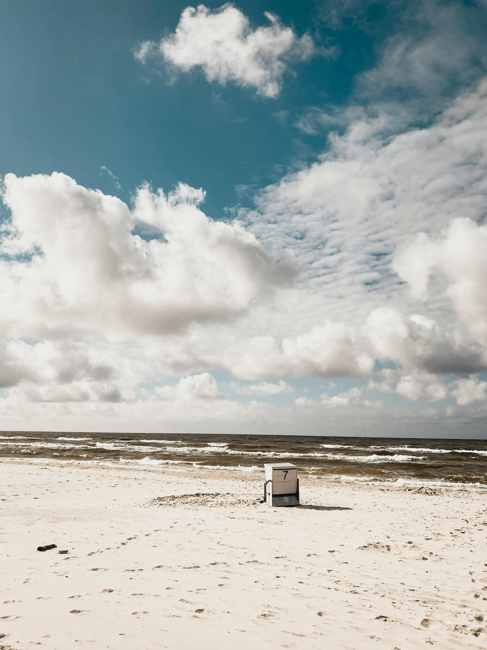 a trash can sits in the middle of a barren beach