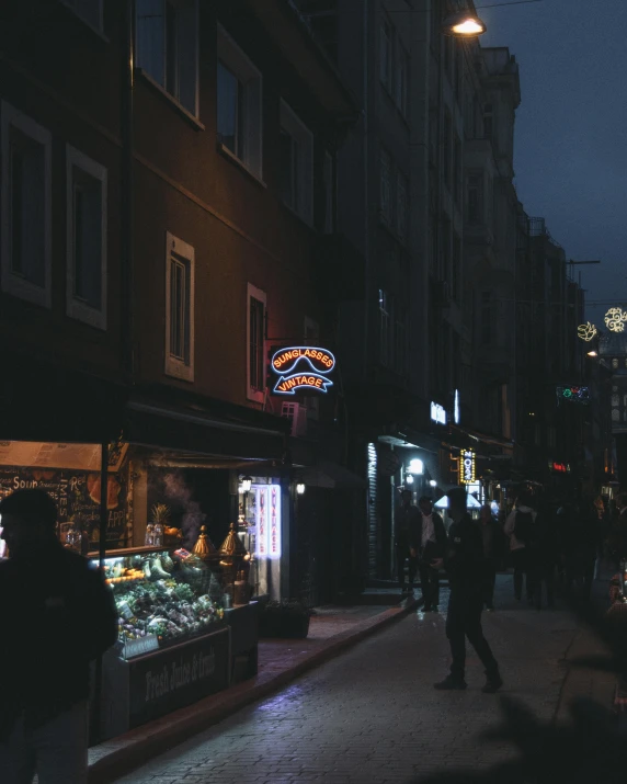 a city street at night with several shops, lit up by neon lights