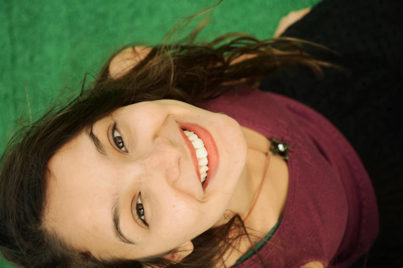 a girl looking up with her teeth and the top of the shirt slightly opened