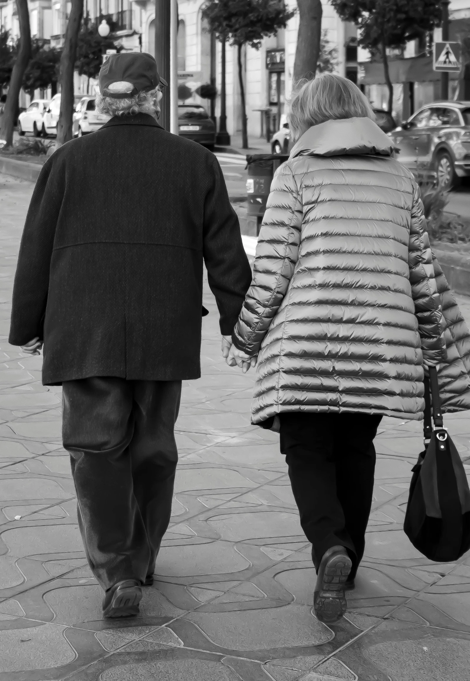 two people walking down the street holding hands