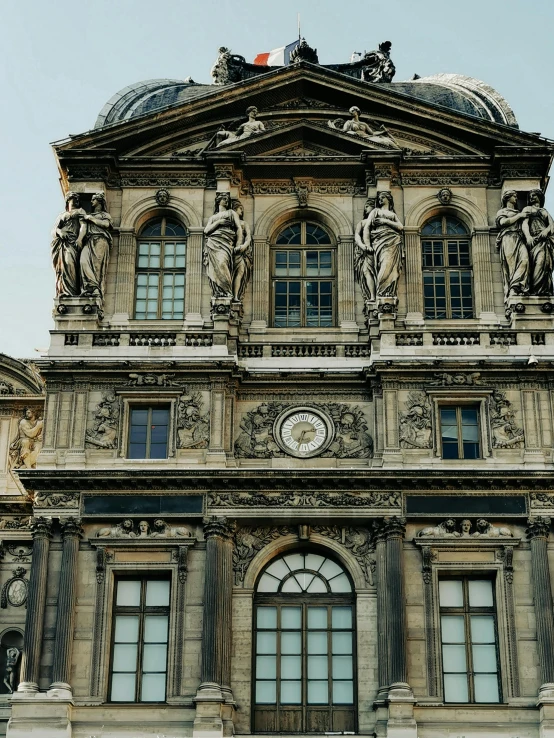 a tall building has an ornate clock and statues