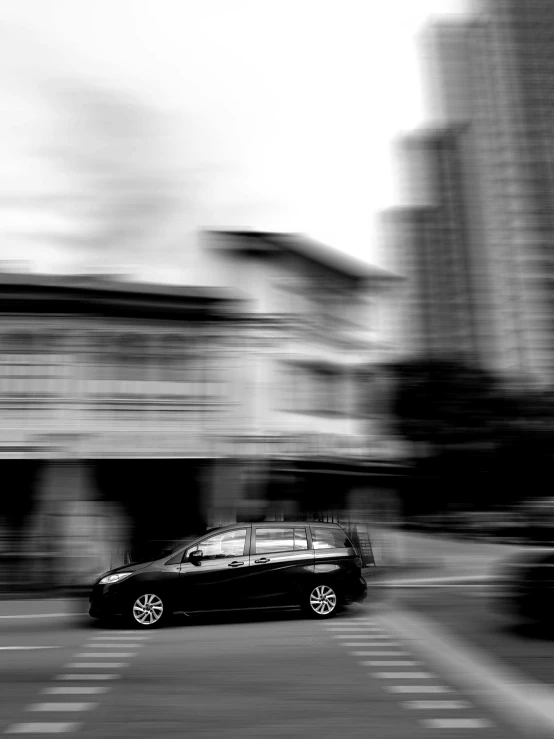 a car drives down the road as a large building towers over it