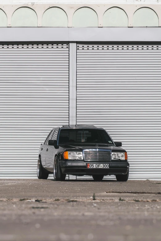 the black car is parked by a closed garage door