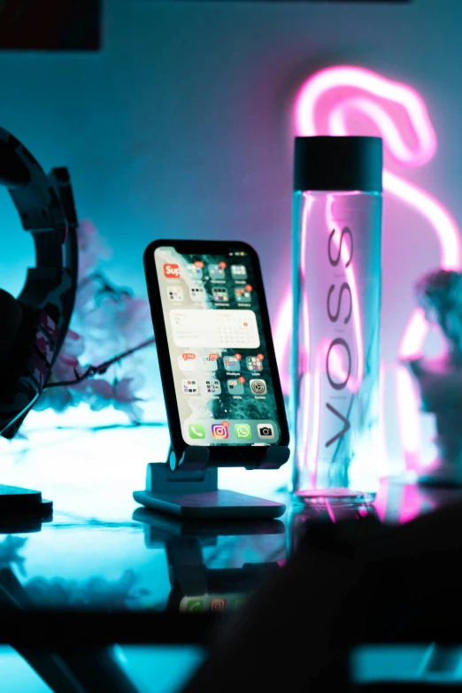 an iphone is charging in front of a water bottle
