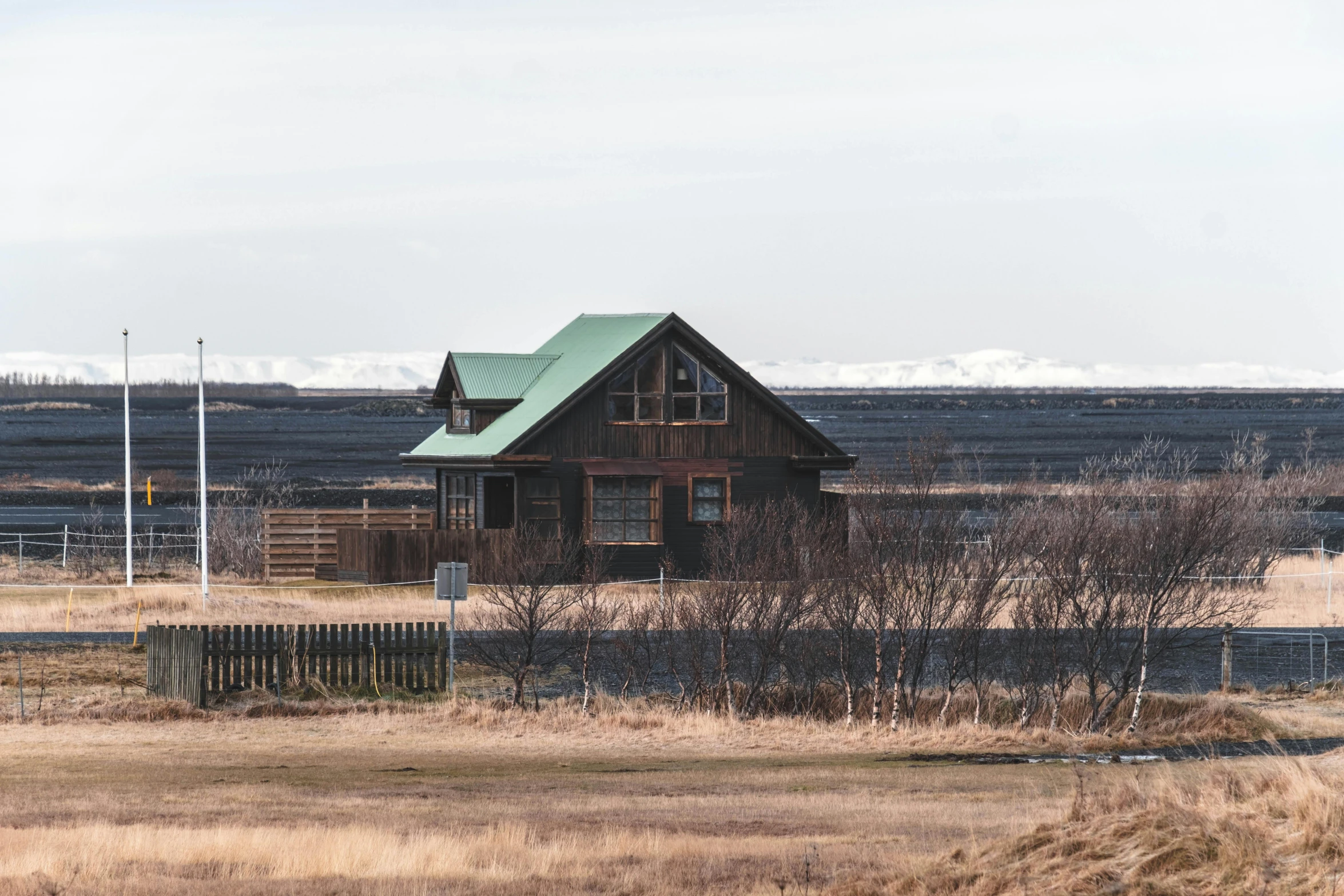 an old house in a field surrounded by dry grass