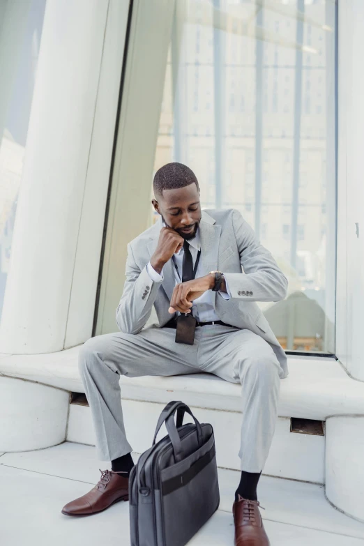 a black man is sitting with his briefcase