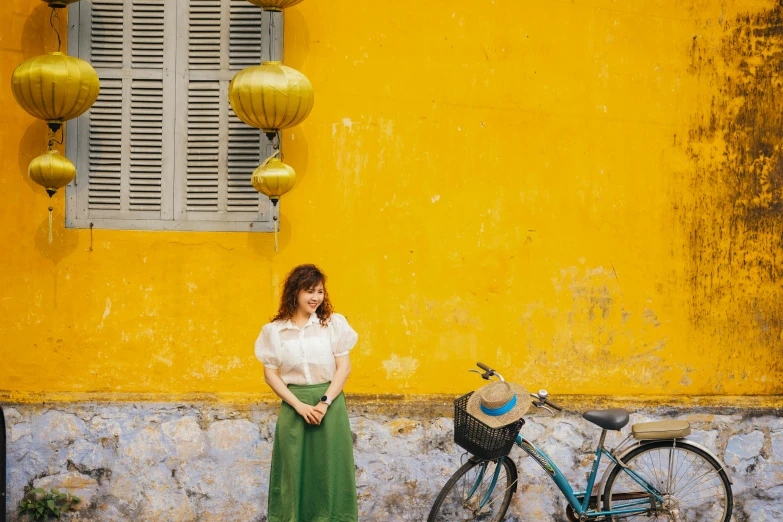 woman standing next to a bike with yellow lanterns hanging off the side of it