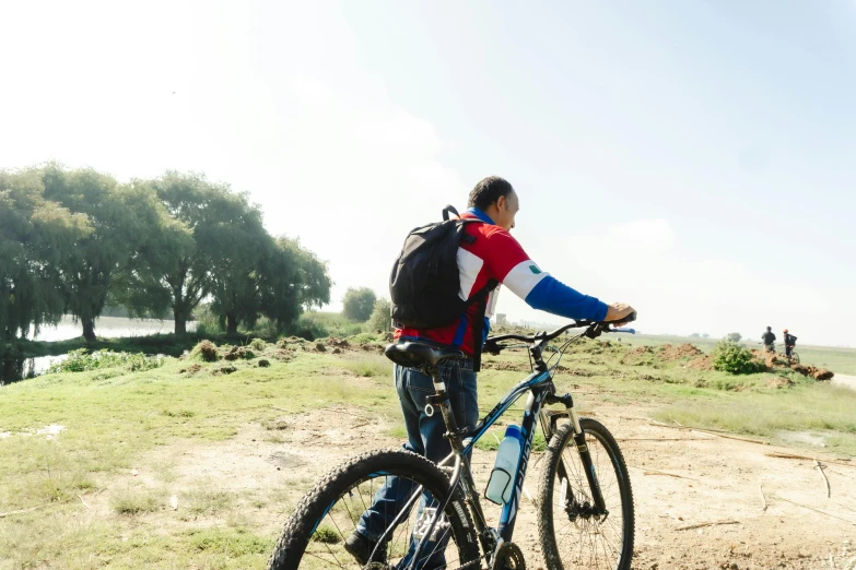 a man stands with his bike and looks out over the landscape