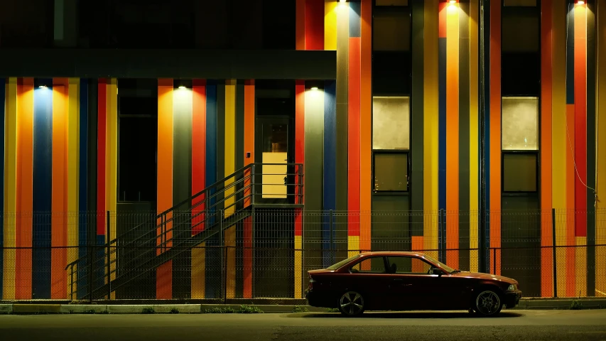 a car is parked outside a building with multi - colored stripes