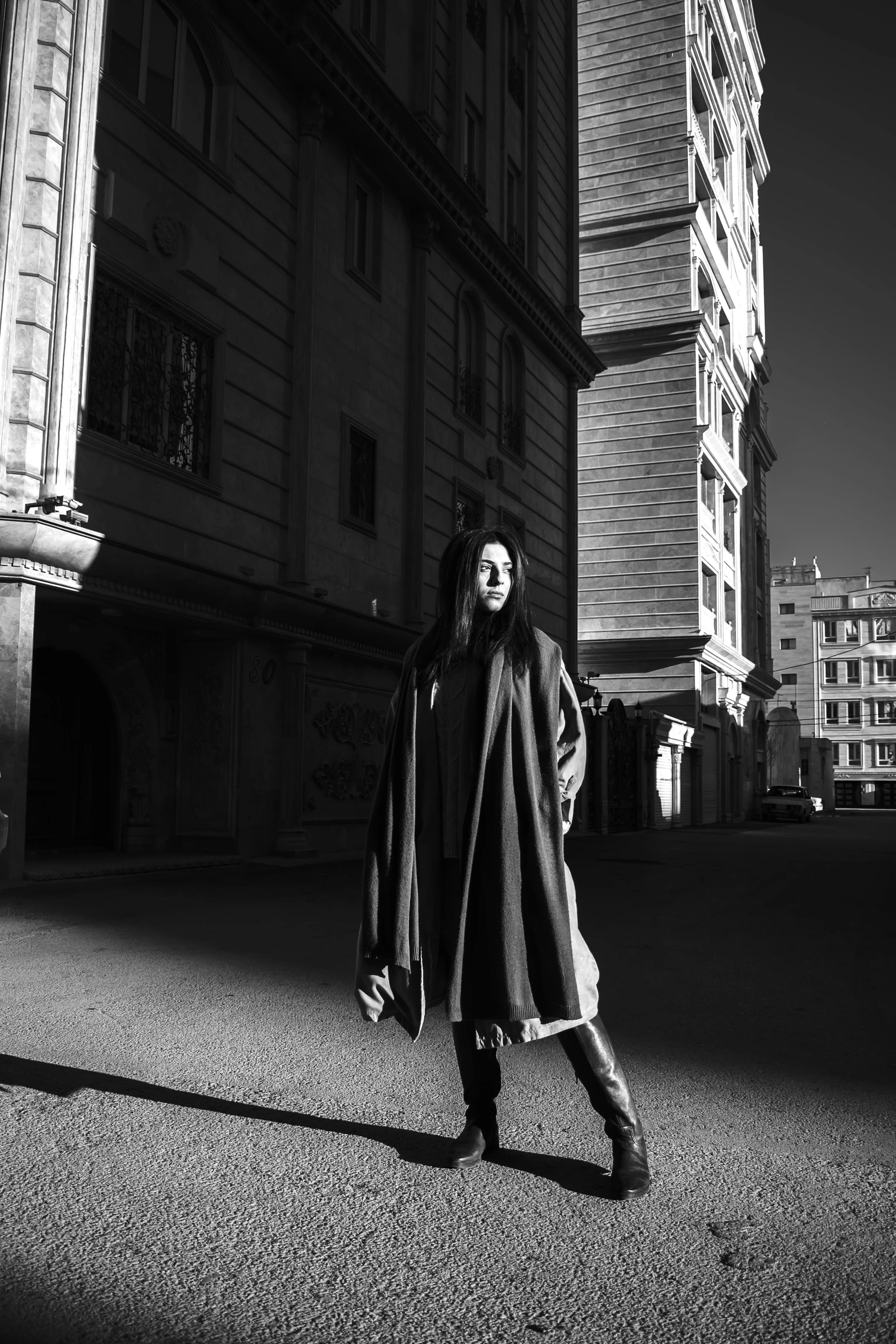 a woman walks on the road in front of buildings