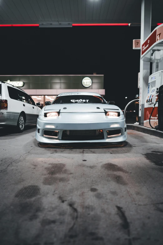 two modified sports cars in a gas station