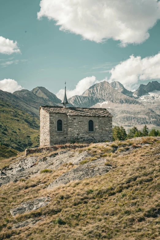 a very small hut sits on top of a grassy hill