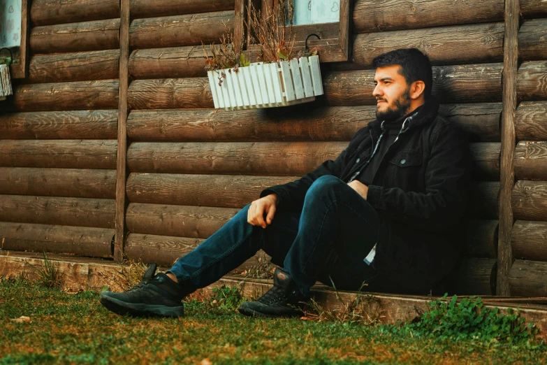 a man sits next to a wooden building