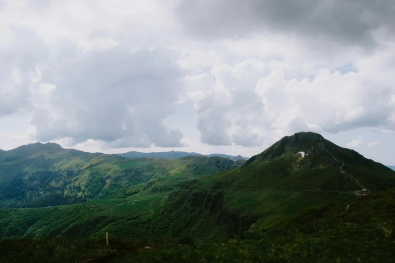 some clouds rolling over mountains with hills on them