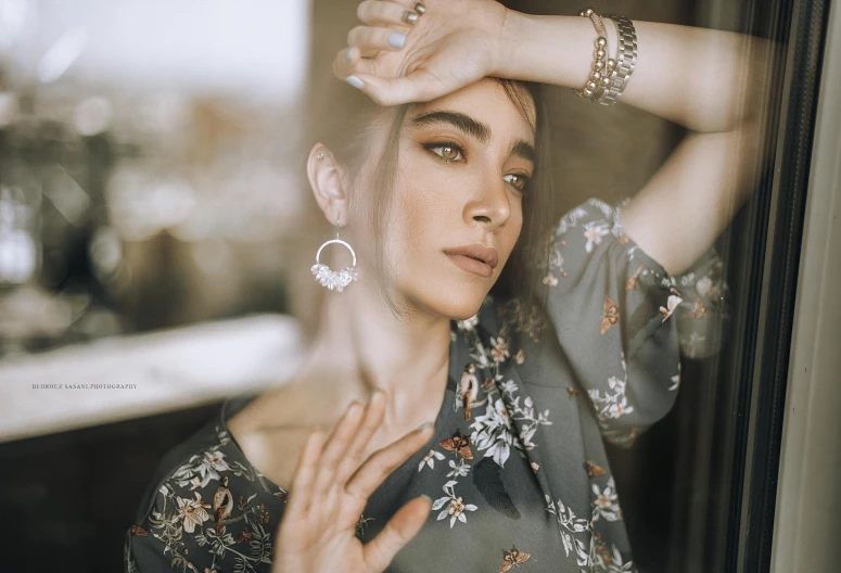 woman in a floral shirt with her hands resting on her head