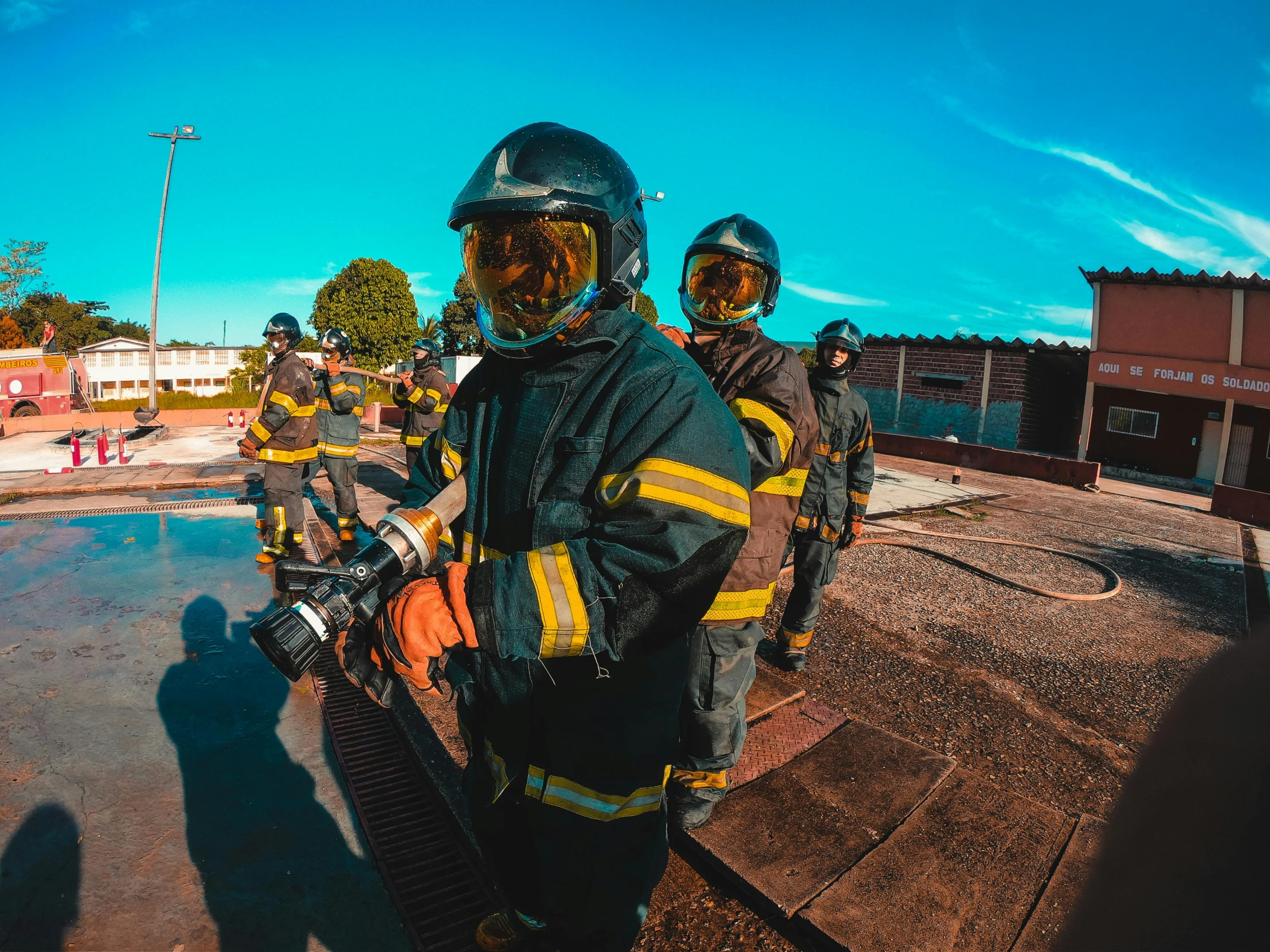 three people in fire suits standing with their motorcycles