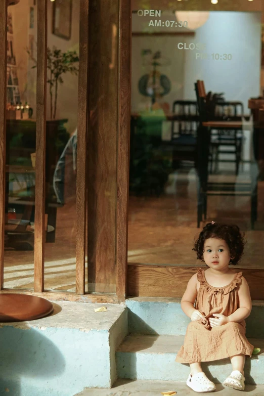 a little girl sitting on the step of a blue house