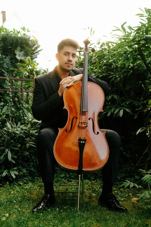 the man is holding his cello in both of his hands