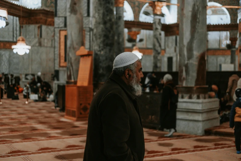 a man standing in a large building with people around him