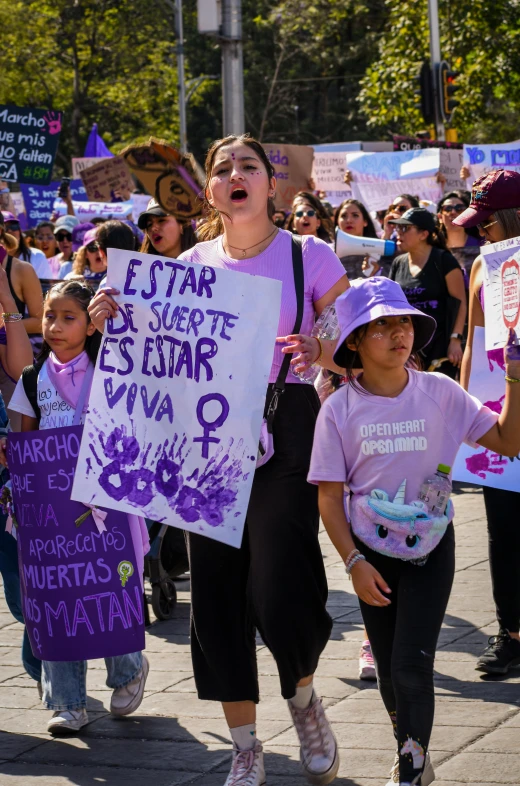 people marching down the street holding signs and talking