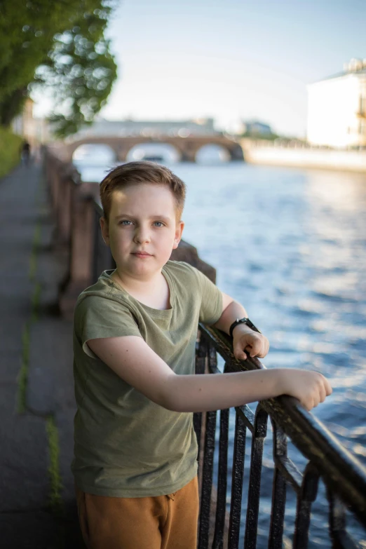 a boy leaning on a rail at the water's edge