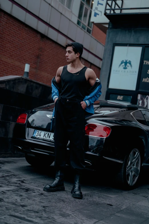 a man in black standing next to a black car