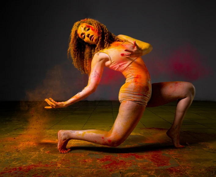 a woman covered in makeup kneeling and making gestures