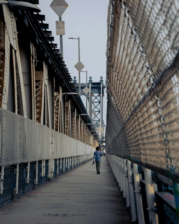 a man walking down a sidewalk next to a bridge