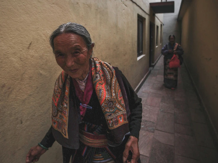 a older person standing near a house with another woman walking down the sidewalk