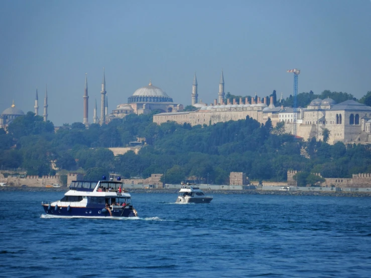 a boat floating on top of a large lake near some buildings