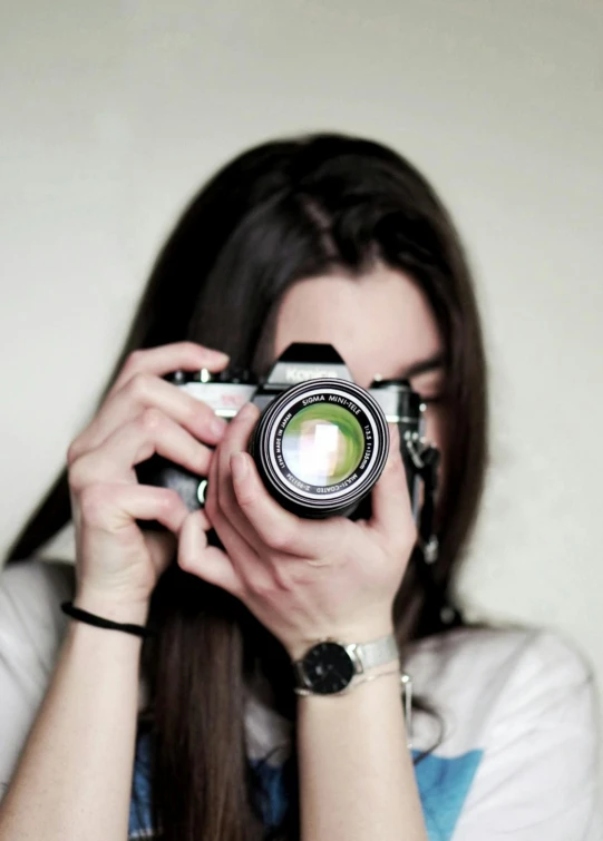 girl taking a po with a camera while holding up a watch