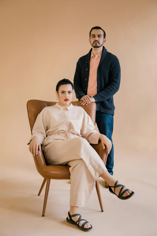 a man and a woman pose for the camera, both of them sit down