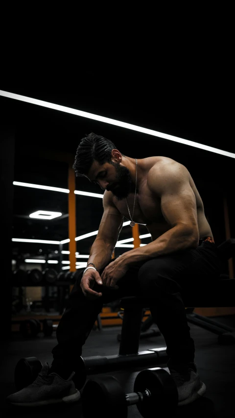 a man sitting in a gym holding his legs crossed