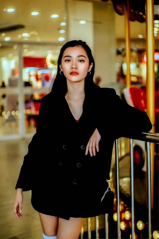 young asian woman in black overcoat posing at railing
