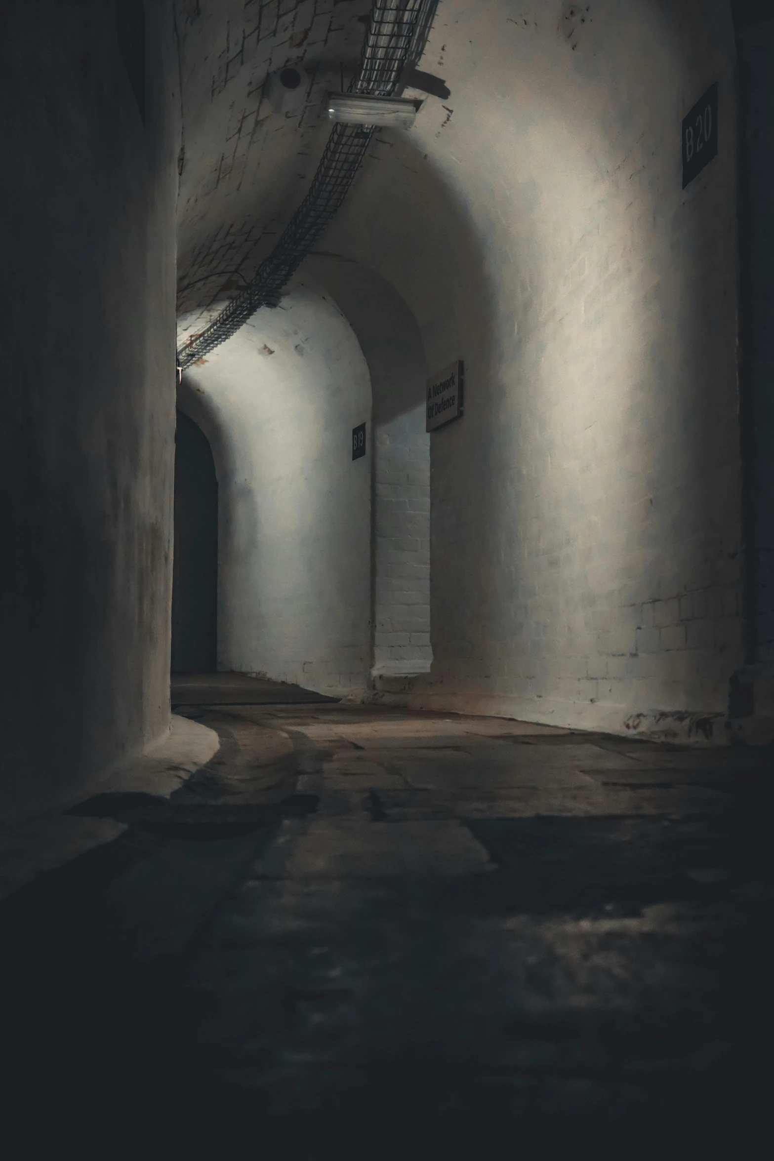 a dimly lit narrow hallway with a cement floor