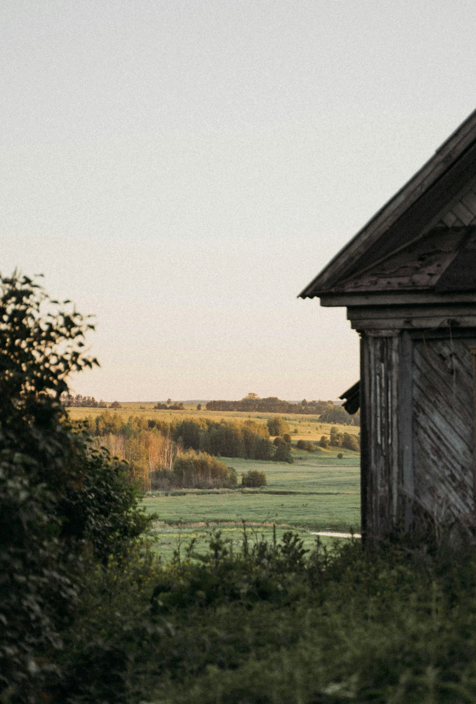 a weathered building in a grassy field at dusk