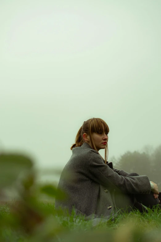 a girl that is sitting in the grass