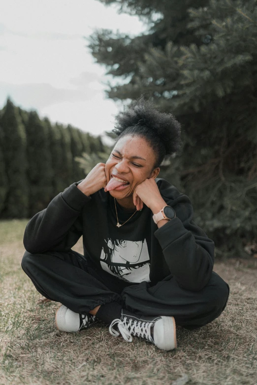 a woman sitting in the grass with her hand on her face