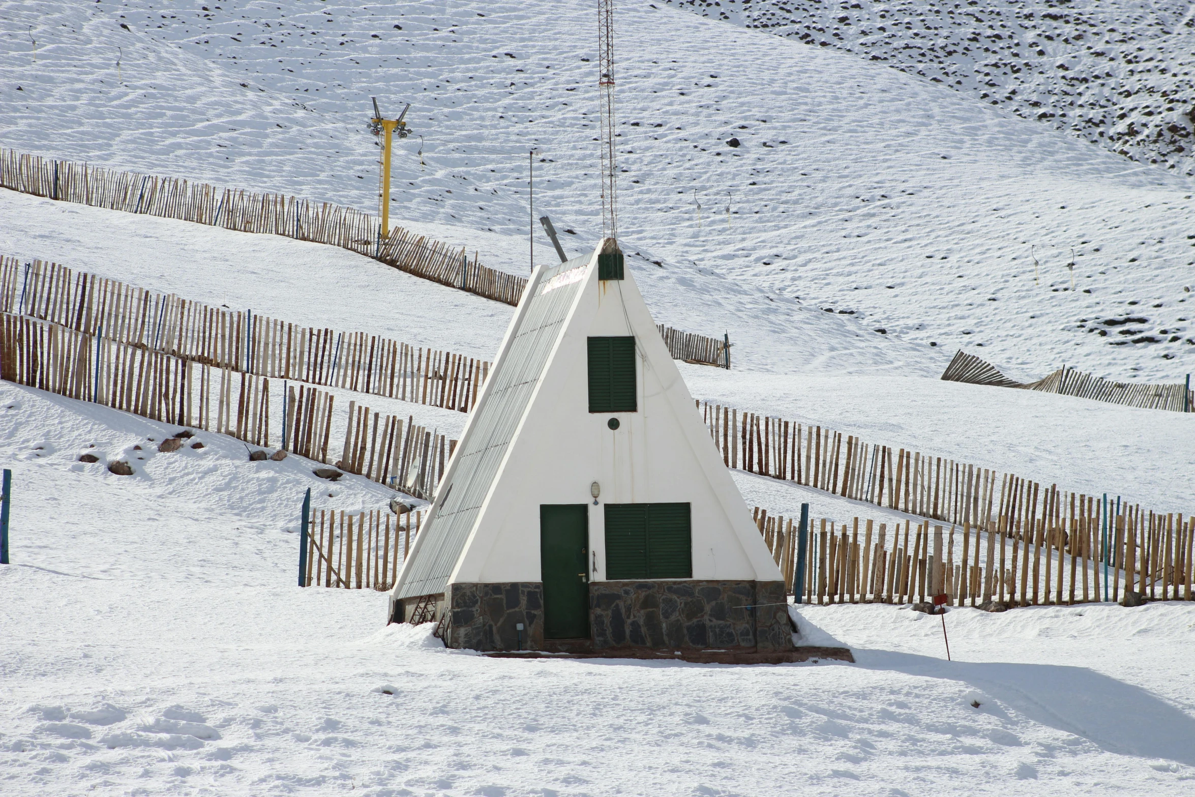 a white building with green door and a roof in the snow