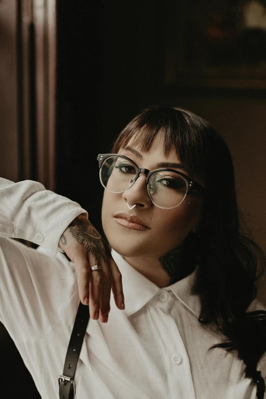 woman with round glasses leaning against the wall