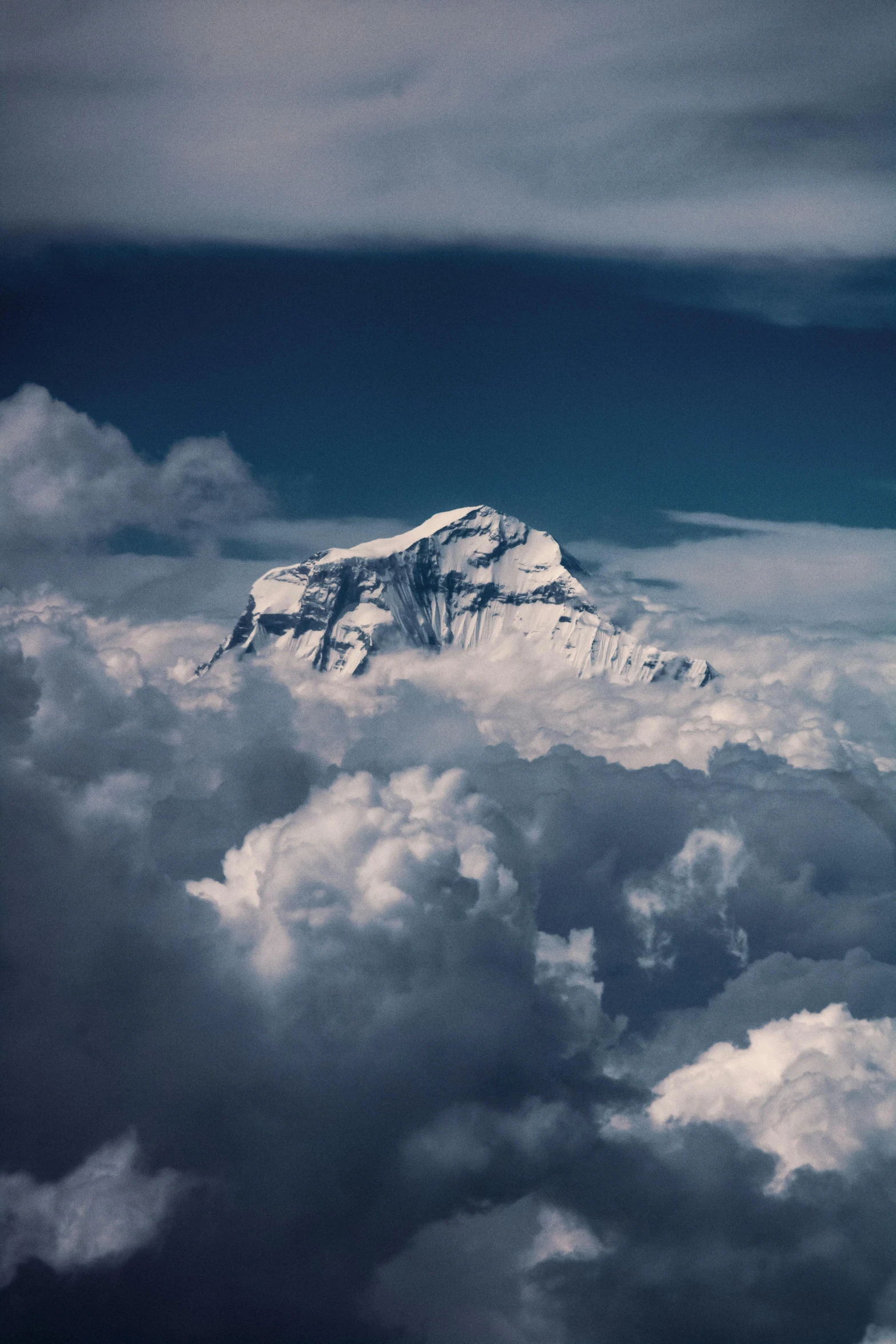 the snow covered mountain tops are high up above the clouds